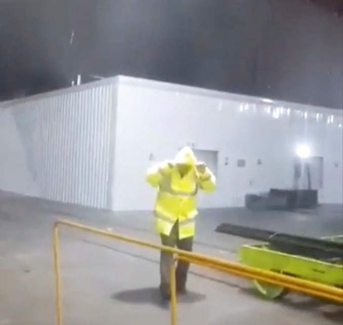 A man wearing a rain jacket walks under heavy rain at Kuwait International Airport in this still image obtained from a social media video November 14, 2018. TWITTER/@canibano32 via REUTERS