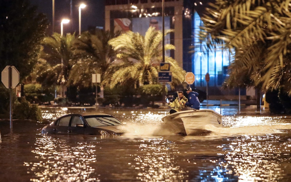 People are having fun with a boat on the flooded main road of the Daeya area of Kuwait city late on November 14, 2018, following heavy rain in the Gulf emirate, four days after flash floods hit the Gulf emirate, killing a man and causing damage to roads, 