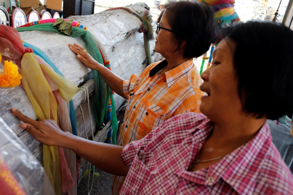 Women rub an ancient bark tree, as they look for lottery lucky numbers at Wat Kunnatri Ruttharam temple in Bangkok, Thailand November 1, 2018. Picture taken November 1, 2018. REUTERS/Jorge Silva