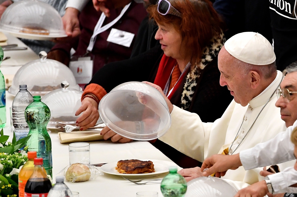 Pope Francis (R) looks at his meal as he has a lunch with destitute people, on November 18, 2018, at the Paul VI audience hall in Vatican, to mark the World Day of the Poor.  AFP / Vincenzo Pinto 
 