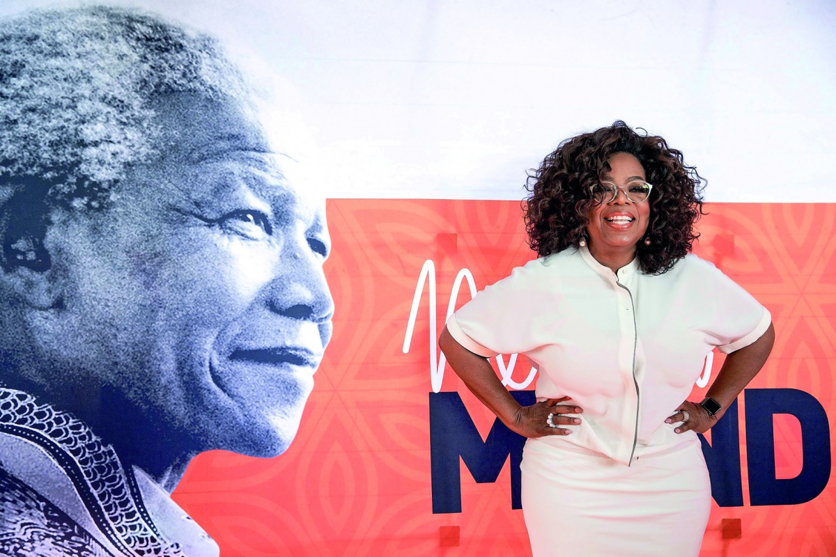 US TV personality Oprah Winfrey poses on the red carpet next to a banner depecting late former South African president Nelson Mandela, as she arrives to attend an event to mark 100 years since the birth of Nelson Mandela, at the University of Johannesburg