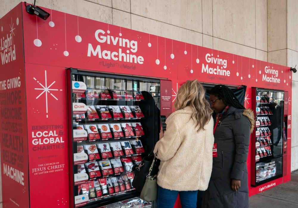 Sister Hicks (C) assists a woman in making a donation at a Giving Machine November 29, 2018 in New York. At right is Sister Davis. AFP / Don Emmert 