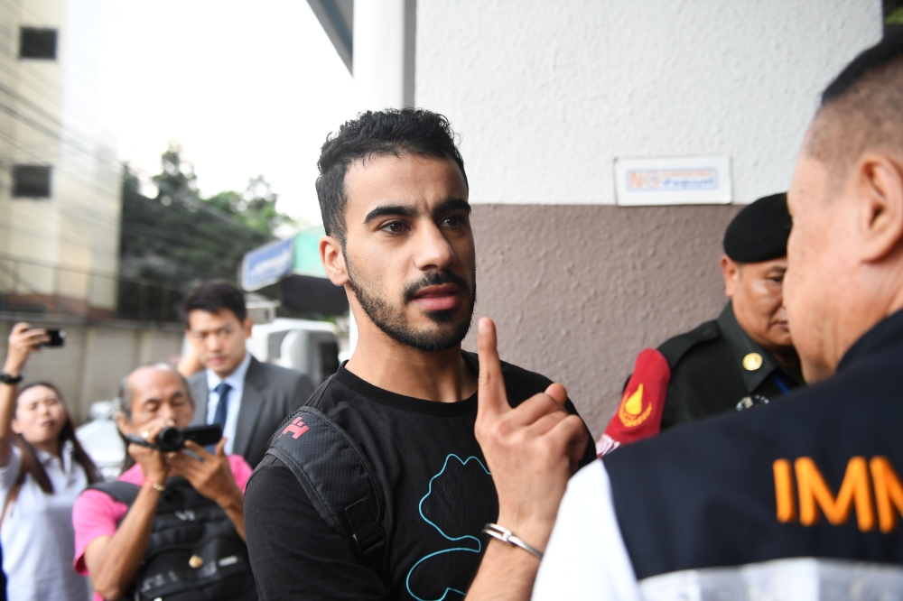 Hakeem Alaraibi (C), a former Bahrain national team footballer with refugee status in Australia, is escorted by immigration police to a court in Bangkok on December 11, 2018. / AFP / Lillian SUWANRUMPHA
 