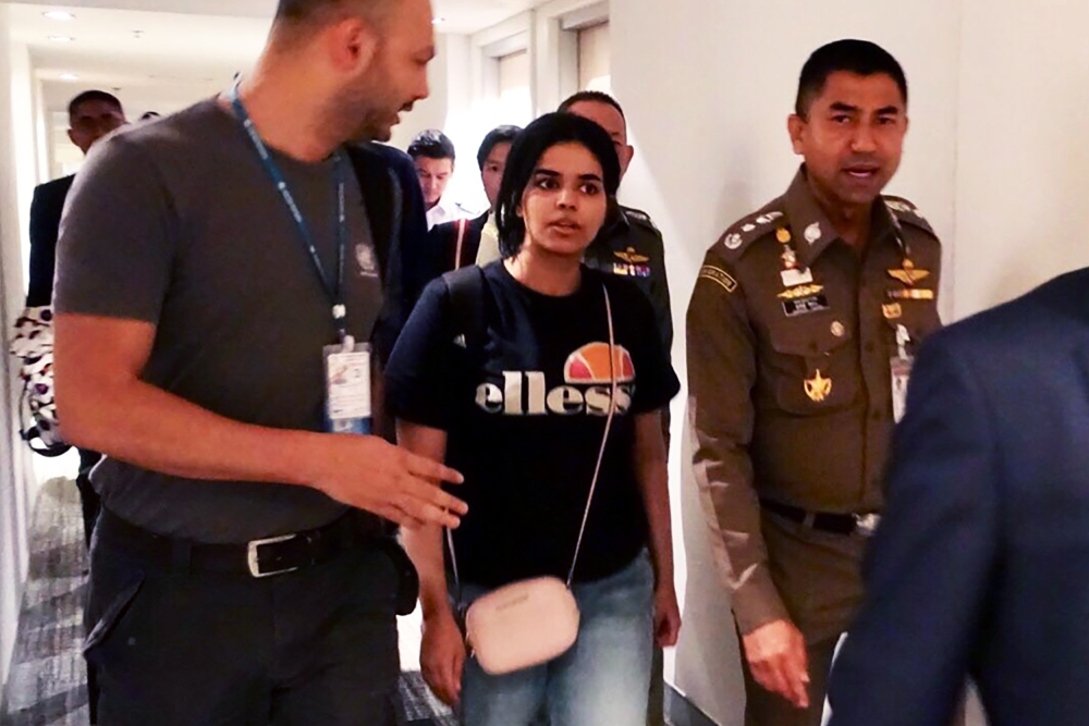 This handout picture taken and released by the Thai Immigration Bureau on January 7, 2019 shows 18-year-old Saudi woman Rahaf Mohammed al-Qanun (C) being escorted by a Thai immigration officer (R) and United Nations High Commissioner for Refugees (UNHCR) 