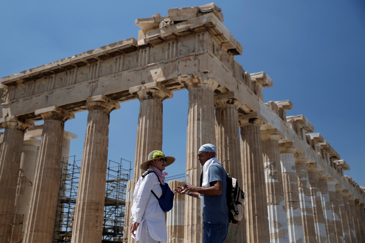 Tourists stand in front of the ancient Parthenon temple atop the Acropolis hill in Athens, August 5, 2017. Reuters/Costas Baltas