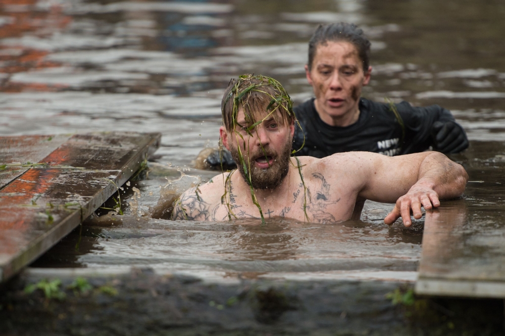 A competitor negotiates a water obstacle in the Tough Guy endurance event near Wolverhampton, central England, on January 27, 2019.  AFP / Oli Scarff 