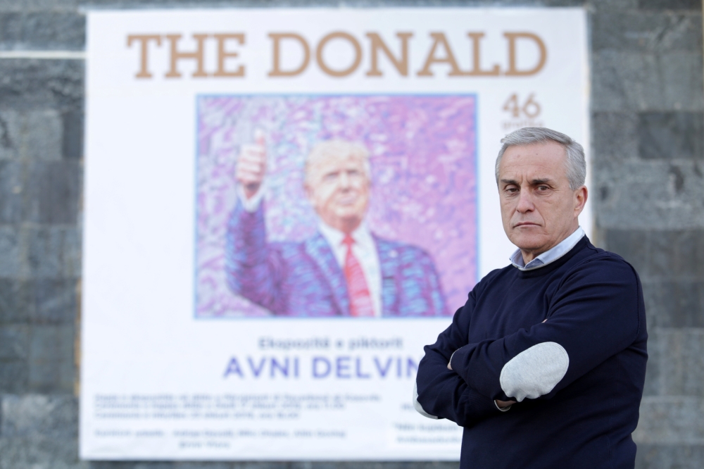 Painter Avni Delvina poses for a picture in front of a poster of his exhibition in the National Museum in Tirana, Albania, February 20, 2019. Reuters/Florion Goga 
 