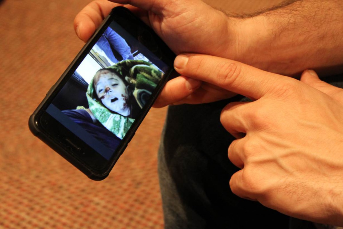 Amer, who is one of 100 White Helmets rescue workers resettled in Britain, shows photos of Syrian children rescued from airstrikes on his phone in his home in northeastern England on 6 March, 2019. Thomson Reuters Foundation/Lin Taylor