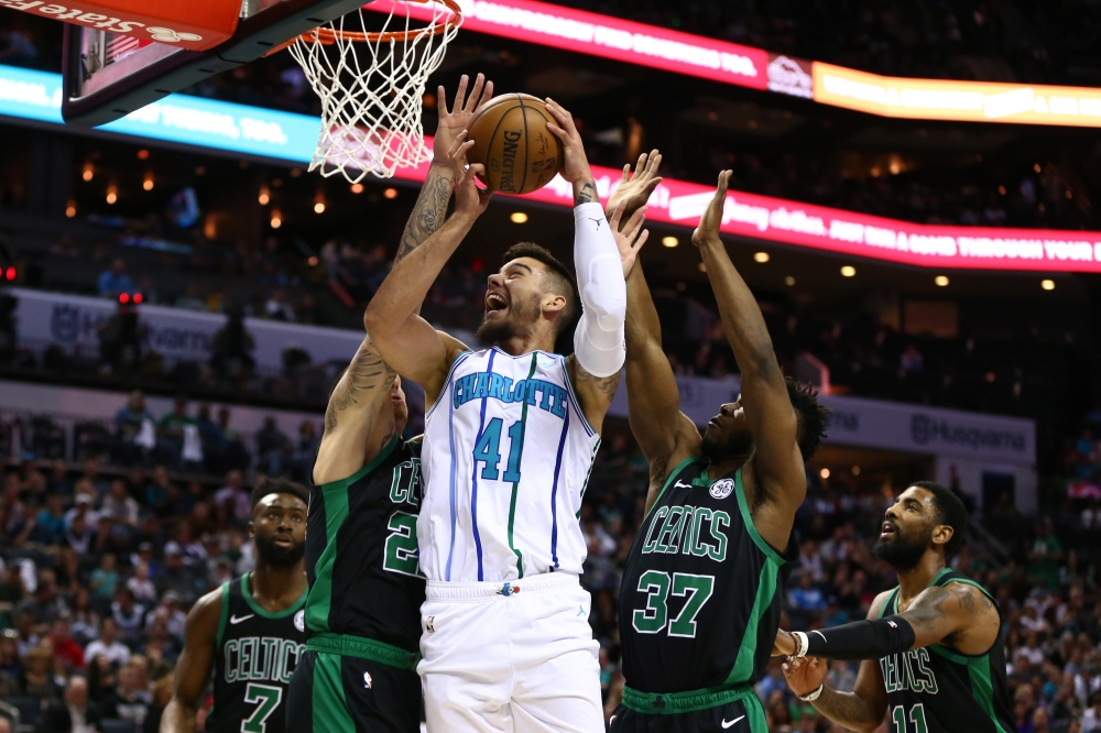 Charlotte Hornets center Willy Hernangomez (41) shoots the ball between Boston Celtics forward Daniel Theis (27) and forward Semi Ojeleye (37) in the first half at Spectrum Center. Jeremy Brevard