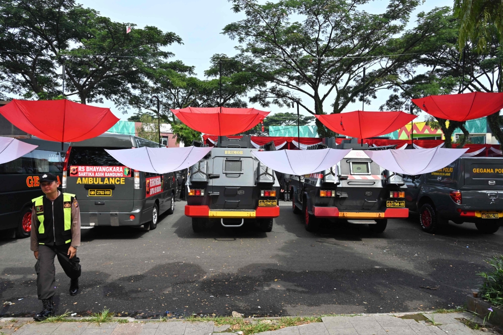 An Indonesia policeman walks next to decorative umbrellas resemble to Indonesia's national flag 