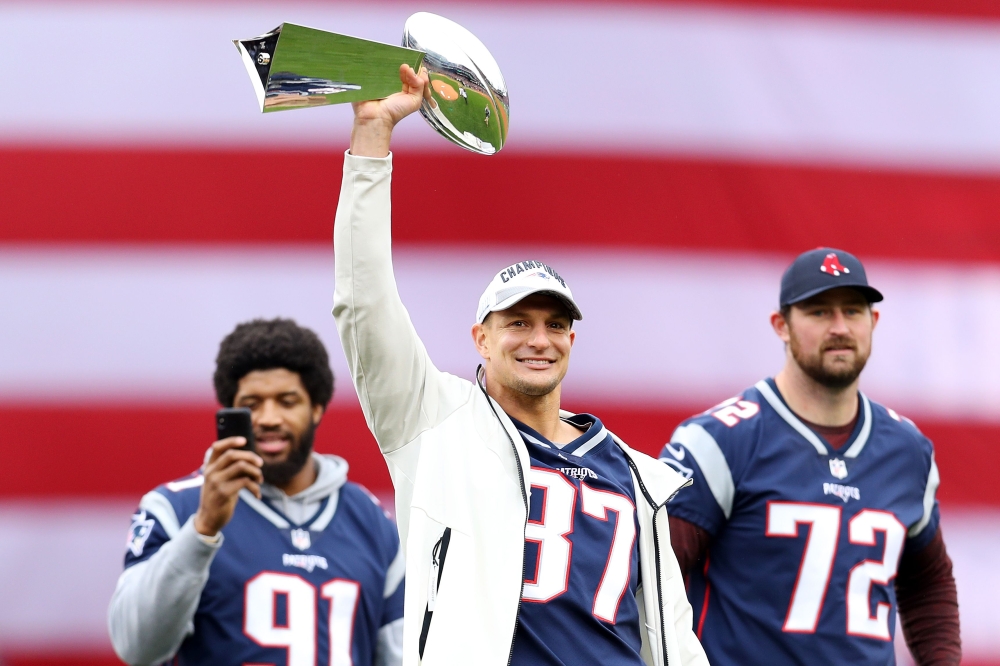 Former New England Patriots player Rob Gronkowski raises the Lombardi Trophy over his head before the Red Sox home opening game against the Toronto Blue Jays at Fenway Park in Boston, Massachusetts, on April 09, 2019. AFP / Getty Images North America / Ma