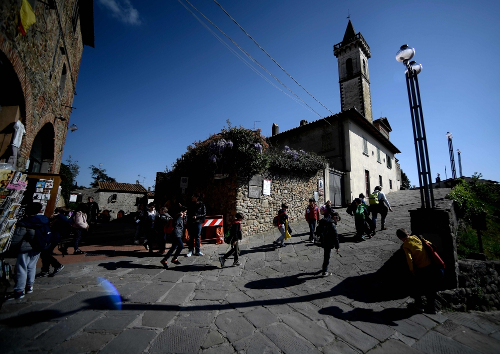 A general view taken on April 9, 2019 shows visitors walking past the Santa Croce church in Vinci, the Tuscan village where Leonardo Da Vinci was born. AFP / Filippo Monteforte 