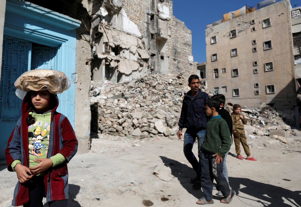 A girl carries a stack of bread on her head as she walks near rubble of damaged buildings in Aleppo's Kalasa district, Syria April 12, 2019. Picture taken April 12, 2019. REUTERS/Omar Sanadiki