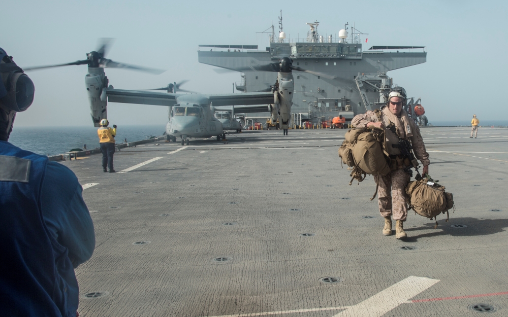 U.S. Marine Corps Gunnery Sgt. David Arendt carries his gear across the flight deck of the USS Lewis B. Puller upon embarkation in the Arabian Gulf, May 11, 2019 . Courtesy Desiree King/U.S. Marine Corps
