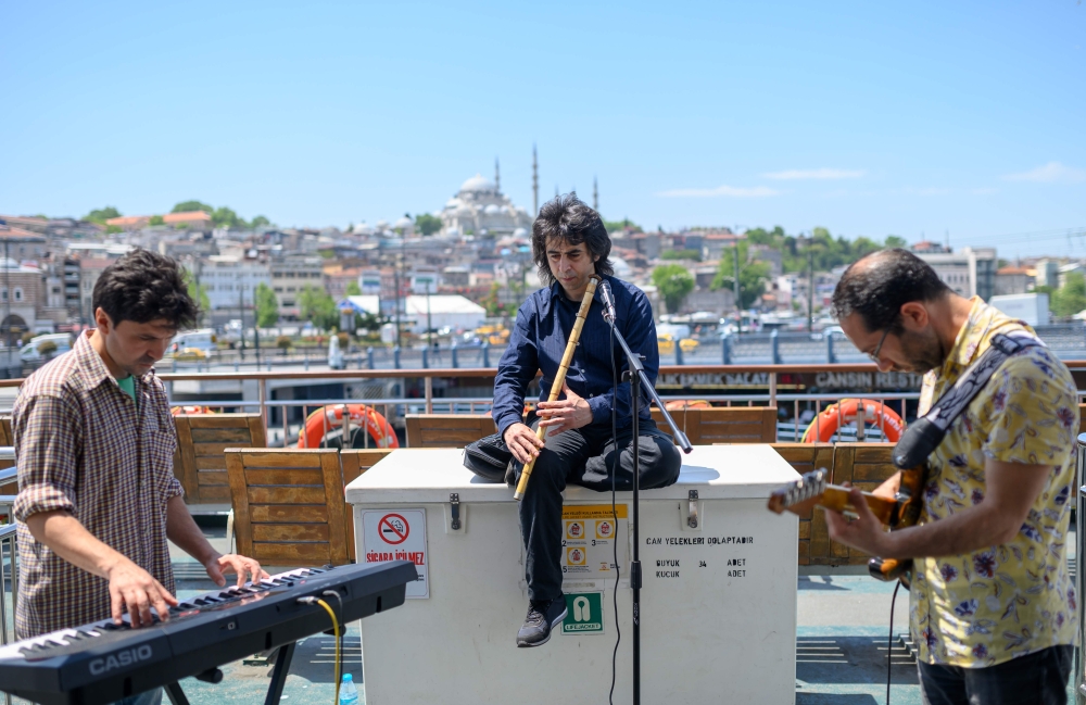 Musicians Oguzhan Erdem (C) plays ney, Eren Koc (L) keyboard and Zafer Saka(R) guitar during a ferry trip on the Bosphorus from Kadikoy to Eminonu, in Istanbul, on May 16, 2019. AFP / BULENT KILIC