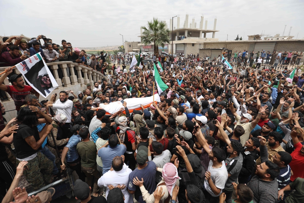 Syrians waving rebel flags and portraits of Abdelbasset al-Sarout during the funeral of the late rebel fighter in al-Dana in Syria's jihadist-controlled Idlib region, near the border with Turkey.  AFP / OMAR HAJ KADOUR