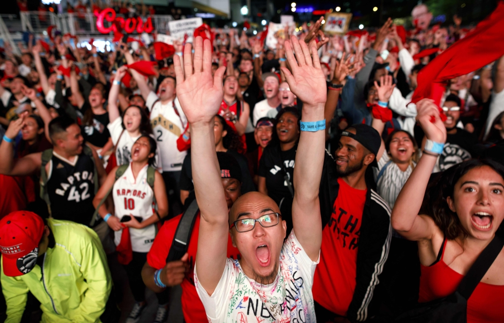 FILE PHOTO: Toronto Raptors fans cheers as they gather to watch Game 4 of the NBA Finals series outside Scotiabank Arena at 'Jurassic Park' in Toronto, Canada.  AFP / GETTY IMAGES NORTH AMERICA / Cole Burston