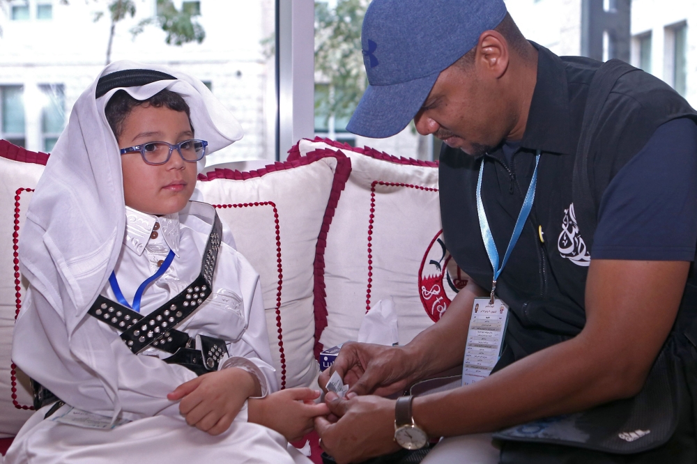 A man tests Qatari child Tamim Abdelmoniem Allafi's blood during the 19th International al-Bawasil Children with diabetes camp in Doha on January 3, 2019. AFP
