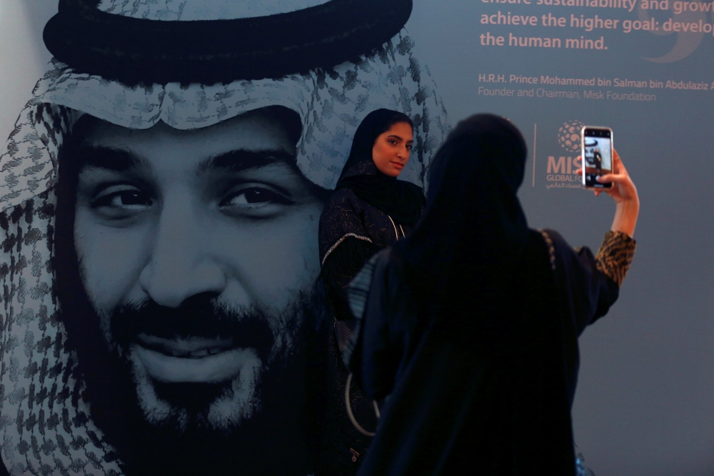 Participants take photos next to a picture of Saudi Crown Prince Mohammed bin Salman during the Misk Global Forum in Riyadh, November 14, 2018. Reuters/Faisal Al Nasser