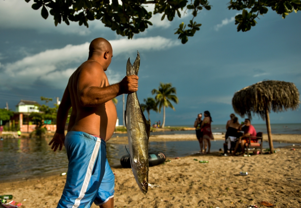 A man carries a fish at Mayabeque beach in Mayabeque province, Cuba, on July 4, 2019. AFP / Yamil Lage 