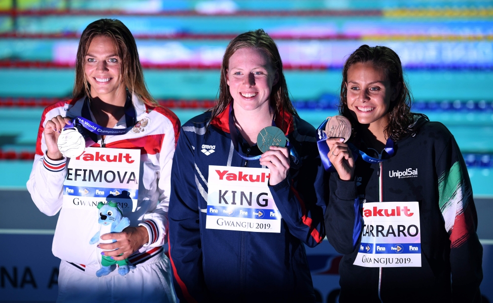 Gold medallist USA's Lilly King (C), silver medallist Russia's Yuliya Efimova (L) and bronze medallist Italy's Martina Carraro (R) pose during the medals ceremony after the final of the women's 100m breaststroke event during the swimming competition at th