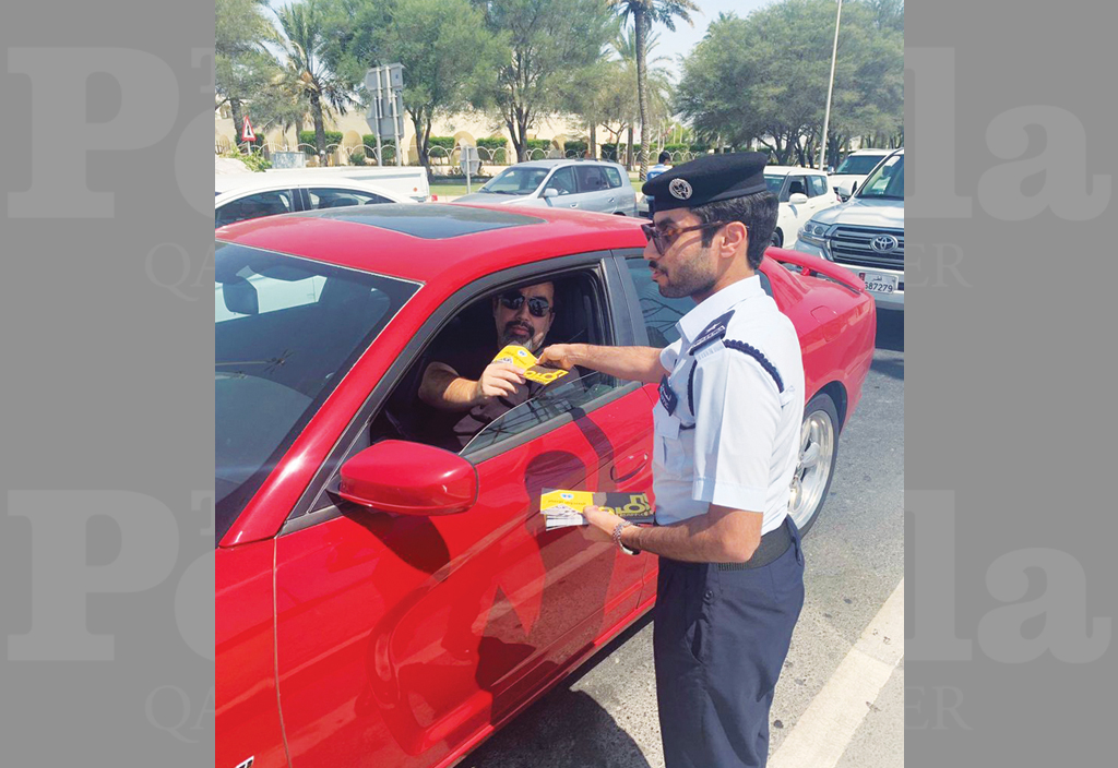 A Traffic Department officer handing over an awareness leaflet to a motorist.