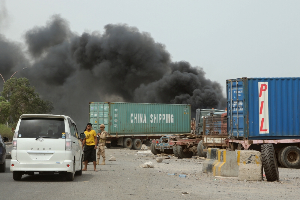 Members of UAE-backed forces stop cars on a street as smoke billows from a car service shop during clashes in Aden, Yemen August 9, 2019. (REUTERS/Fawaz Salman)