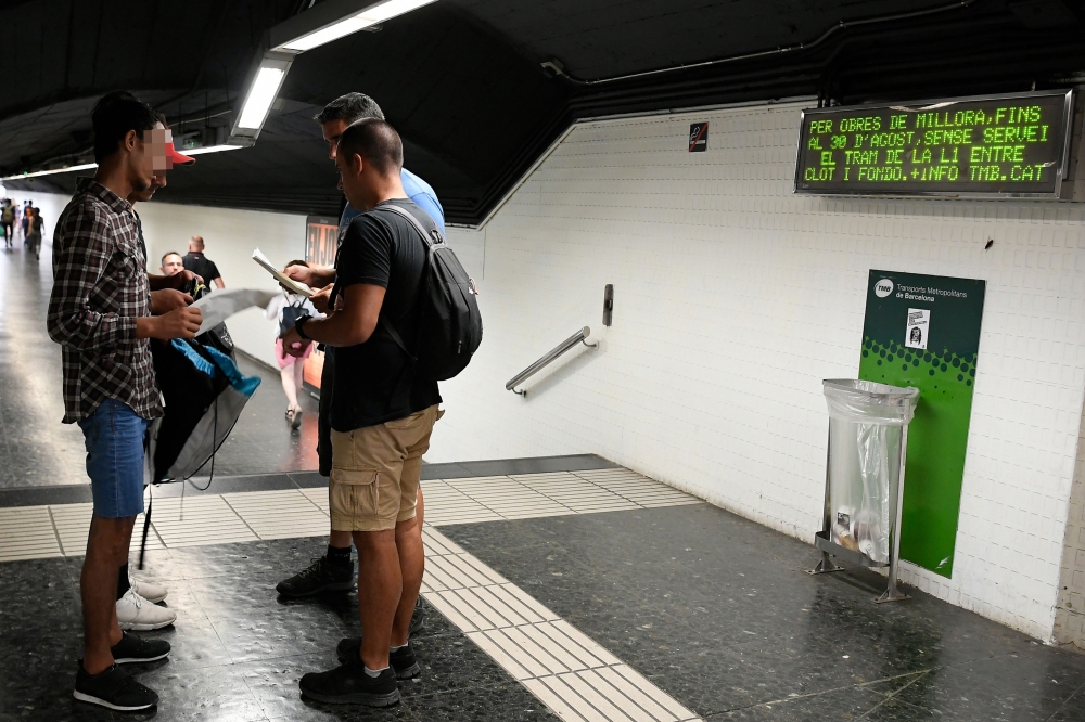 Two police officers in plainclothes check the identification documents of two presumed pickpockets (L) at a metro station in Barcelona on August 14, 2019.  AFP / Lluis Gene
 


. Pictures by Lluis Gene
