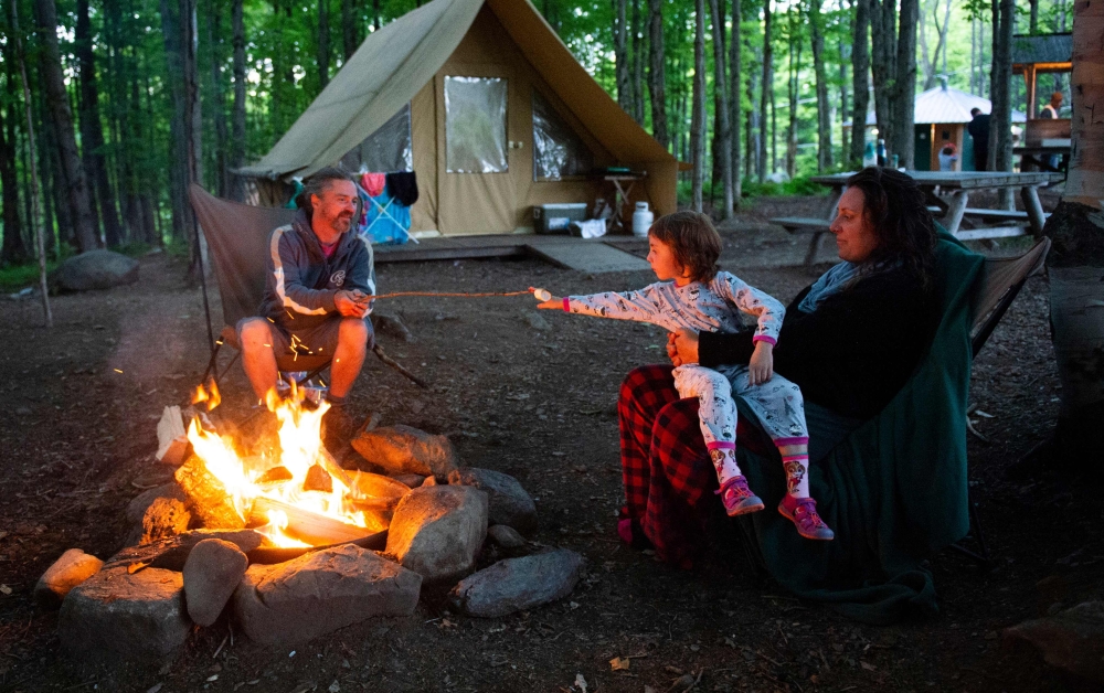 A family enjoys a campfire at the Huttopia Sutton glamping ground in Quebec, Canada, on August 14, 2019.  AFP / Sebastien St-Jean