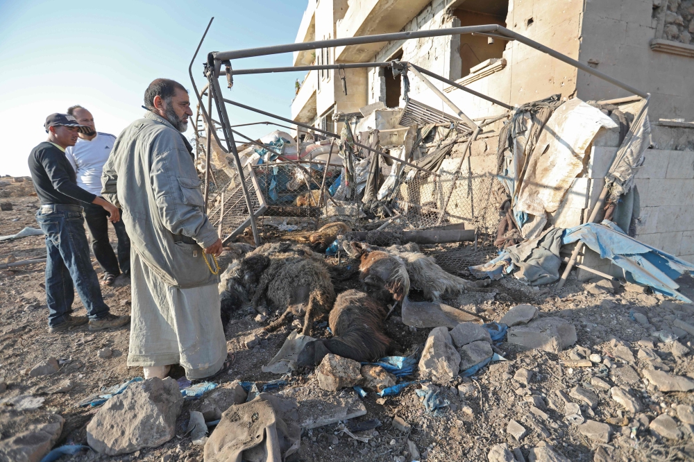 Syrian men look at a destroyed sheep pen following a reported Russian air strike in the village of al-Daher in Syria's northwestern Idlib province on September 11, 2019.  AFP / Omar HAJ KADOUR