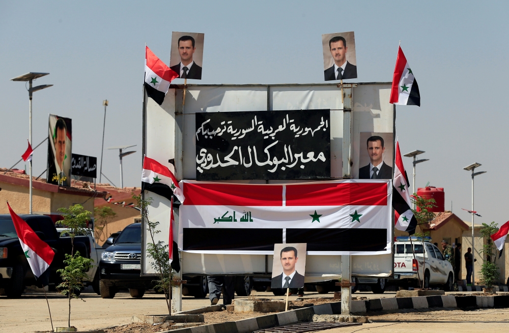 Posters of Syrian President Bashar al-Assad are seen at the Iraqi-Syrian border, after it has been reopened for trade and travel, in Al Qaim, Iraq September 30, 2019. REUTERS/Thaier Al-Sudani