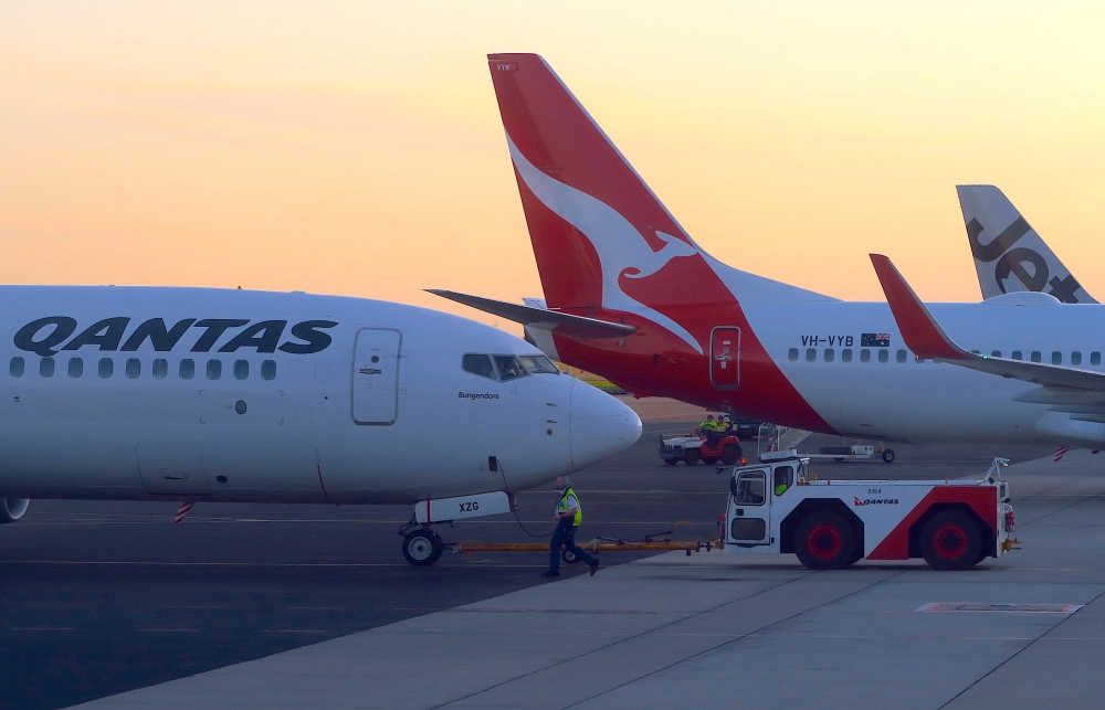 FILE PHOTO: Workers are seen near Qantas Airways, Australia's national carrier, Boeing 737-800 aircraft on the tarmac at Adelaide Airport, Australia, August 22, 2018. REUTERS/David Gray/File Photo