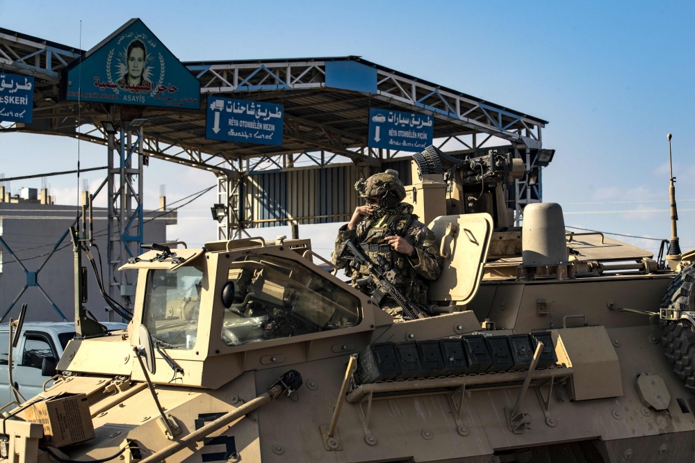 A US soldier sits atop an armoured personnel carrier in the Kurdish-majority city of Qamishli, in Syria's northeastern Hasakeh province on November 2, 2019. / AFP / Delil SOULEIMAN