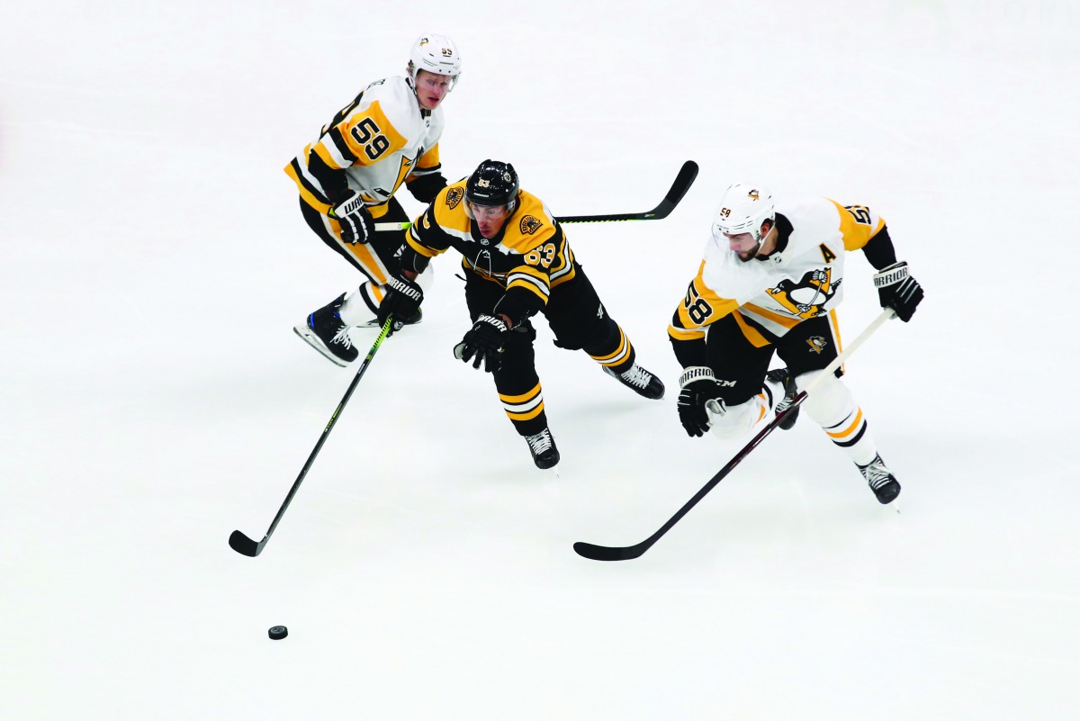 Brad Marchand #63 of the Boston Bruins battles for the puck with Jake Guentzel #59 and Kris Letang #58 of the Pittsburgh Penguins during the first period at TD Garden on November 04, 2019 in Boston, Massachusetts. Tim Bradbury/Getty Images/AFP