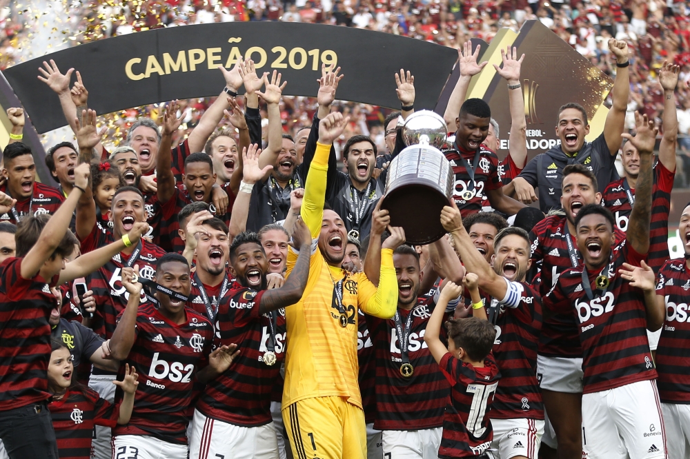 Players of Brazil's Flamengo celebrate on the podium with the trophy after winning the Copa Libertadores final football match by defeating Argentina's River Plate, at the Monumental stadium in Lima, on November 23, 2019. / AFP / Luka GONZALES