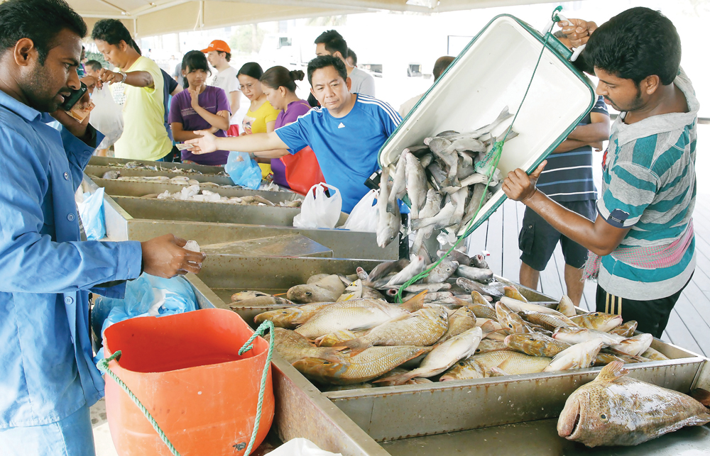 Customers buying fish from a vendor at fish market.