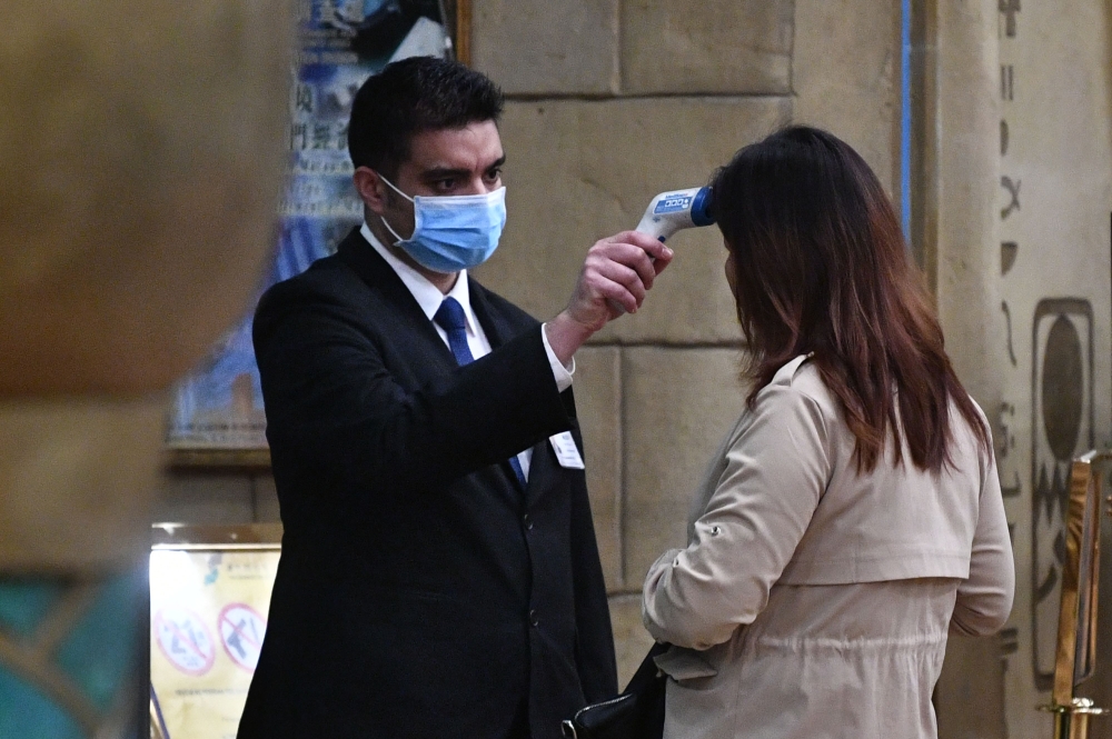 A staff member checks the temperature of a guest entering the New Orient Landmark hotel in Macau on January 22, 2020, after the former Portuguese colony reported its first case of the new SARS-like virus that originated from Wuhan in China. AFP / Anthony 