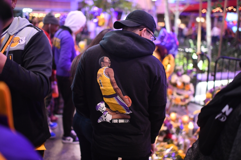 People gather in front of a makeshift memorial as they mourn the death of NBA legend Kobe Bryant at LA Live plaza in front of Staples Center in Los Angeles on January 27, 2020.   AFP / Robyn Beck