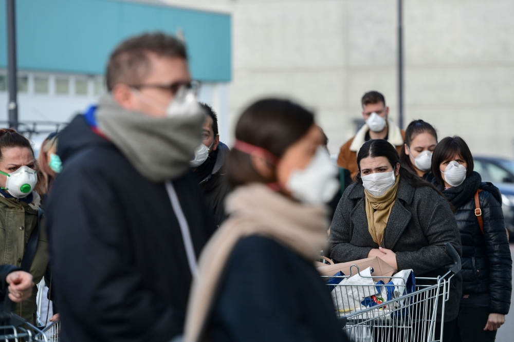 Residents wearing respiratory mask wait to be given access to shop in a supermarket in small groups of forty people on February 23, 2020 in the small Italian town of Casalpusterlengo, under the shadow of a new coronavirus outbreak, as Italy took drastic c