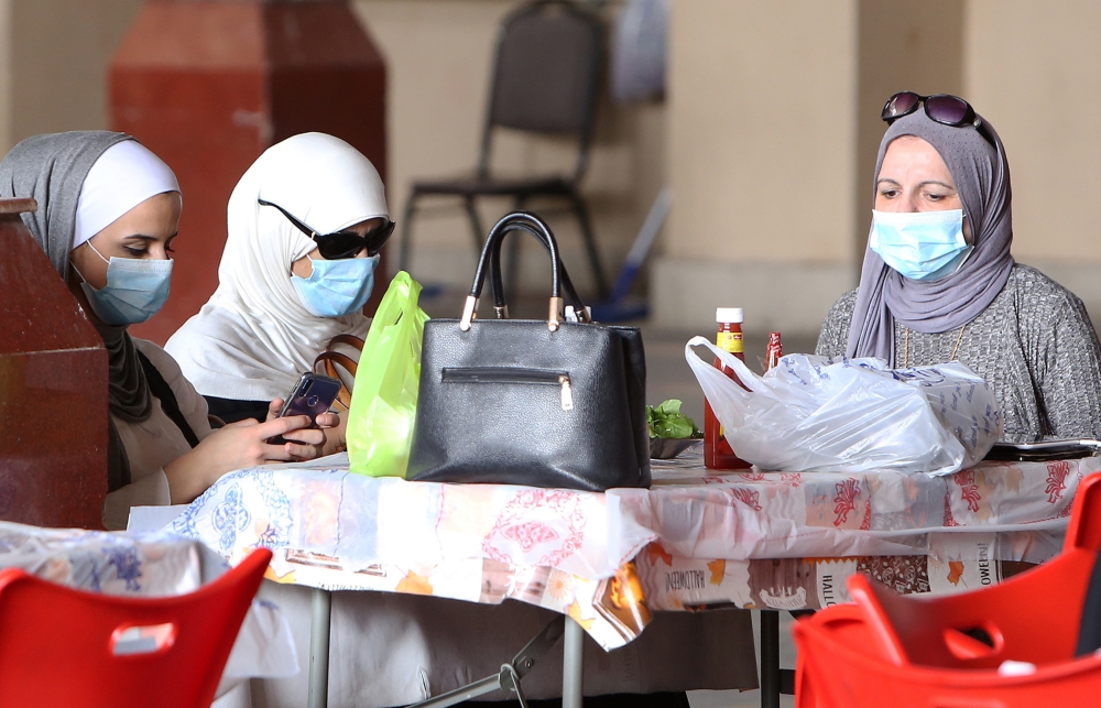 Kuwaiti women wear protective masks as they sit in a restaurant inside the Mubarakiya Market in Kuwait City on February 24, 2020. AFP / YASSER AL-ZAYYAT