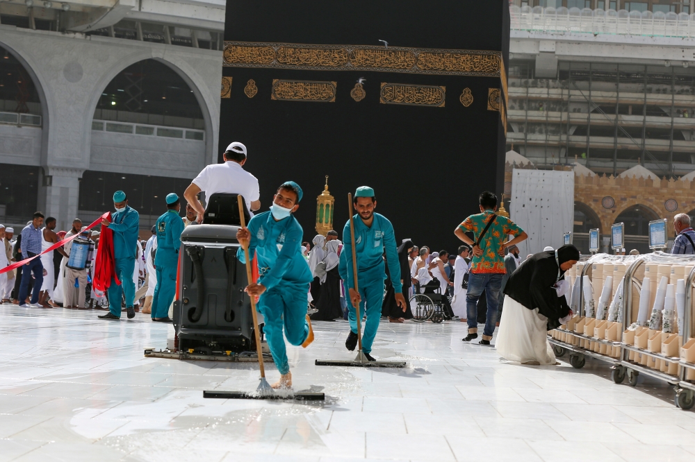 Cleaners wear protective face masks, following the outbreak of the coronavirus, as they swipe the floor at the Kaaba in the Grand mosque in the holy city of Mecca, Saudi Arabia March 3, 2020. REUTERS/Ganoo Essa