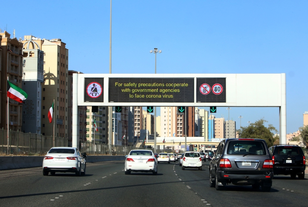 Vehicles pass by a billboard showing precautionary instructions against the COVID-19 coronavirus disease as they drive along a main highway in Kuwait City on March 3, 2020. / AFP / YASSER AL-ZAYYAT 