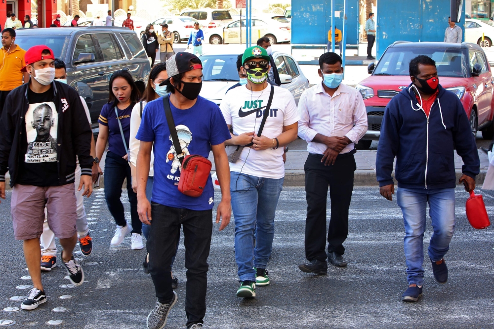 People wearing protective masks cross the street in Kuwait City on March 2, 2020, amid a global outbreak of the novel Coronavirus. / AFP / YASSER AL-ZAYYAT