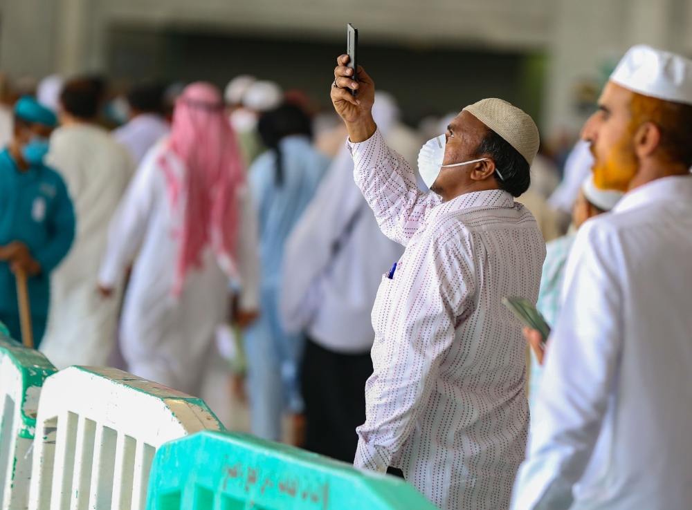 A worshipper wearing a protective mask, takes photographs around Mecca's Grand Mosque on March 6, 2020. AFP / Abdel Ghani BASHIR