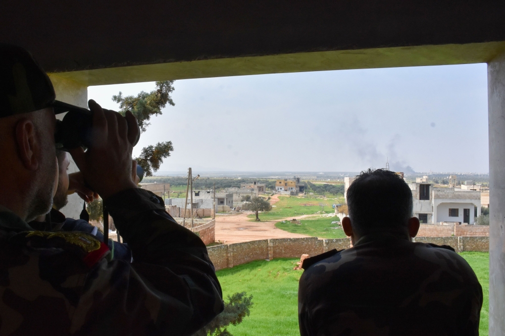 Syrian army soldiers watch over the Turkish and Russian military joint patrol on the M4 highway, which links the northern Syrian provinces of Aleppo and Latakia, on March 15, 2020.   AFP 