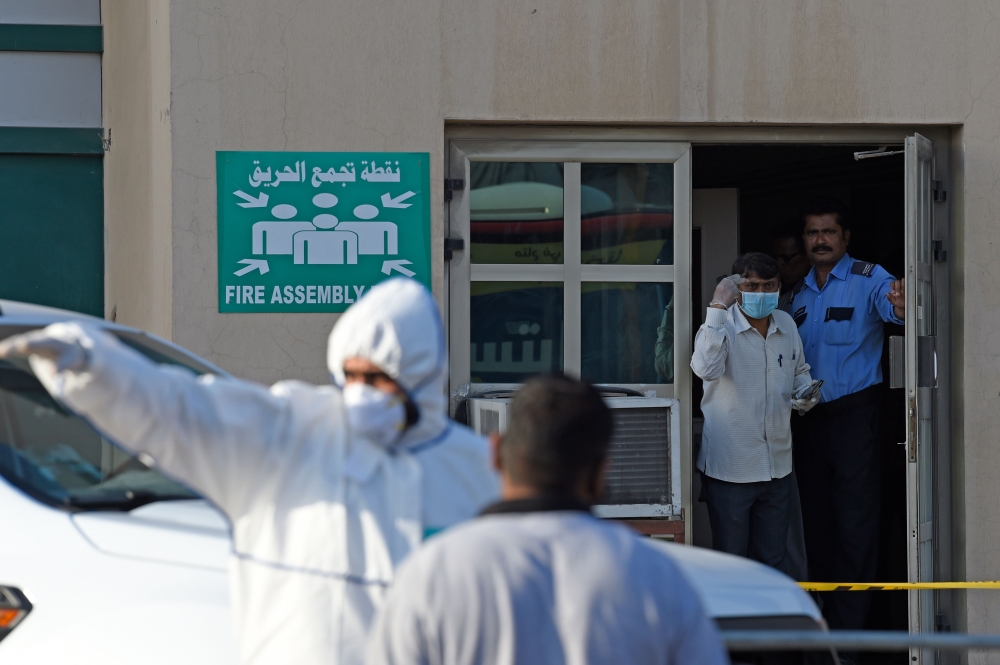 Bahraini policemen seal off a building housing foreign workers in the Salmabad industrial area as a precautionary measure after a resident tested positive for coronavirus (COVID-19), on the outskirts of the capital Manama on March 13, 2020. / AFP / Mazen 