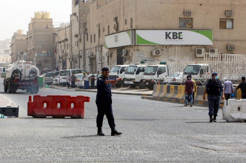 FILE PHOTO: Kuwaiti police officers man a checkpoint at the entrance the town of Jeleeb Al-Shuyoukh, south the capital Kuwait City on April 7, 2020, after the district was put on lockdown. / AFP / YASSER AL-ZAYYAT