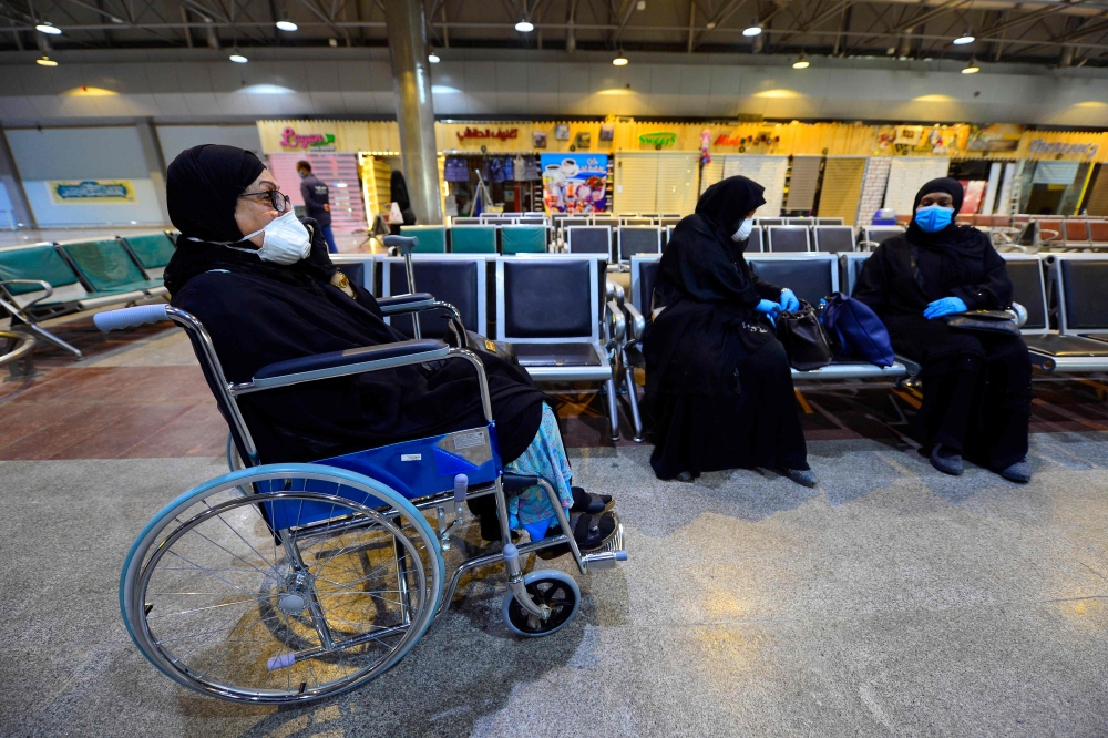 A wheelchair-bound woman waits with other Kuwaiti nationals for a repatriation flight at Najaf International Airport on May 5, 2020, after being quarantined at a hotel in Iraq's central holy shrine city of Najaf. / AFP / Haidar HAMDANI