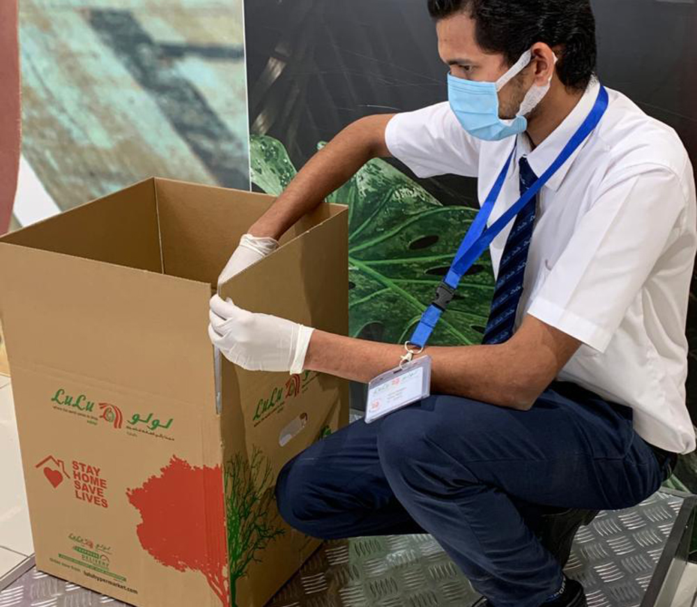 A Lulu Hypermarket staff preparing a carton for delivery.