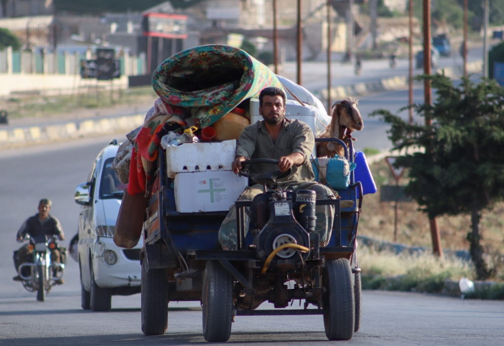 A displaced Syrian man drives his agricultural vehicle loaded with belongings as he flees along the M4 highway, in Ariha in the rebel-held northwestern Syrian province of Idlib, on June 8, 2020, heading north. / AFP / Abdulaziz KETAZ